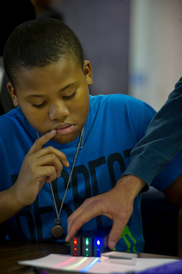 a 6th grade student using red green and blue ray box from Laser Classroom to measure refraction through a trapezoid prism lens on a desk
