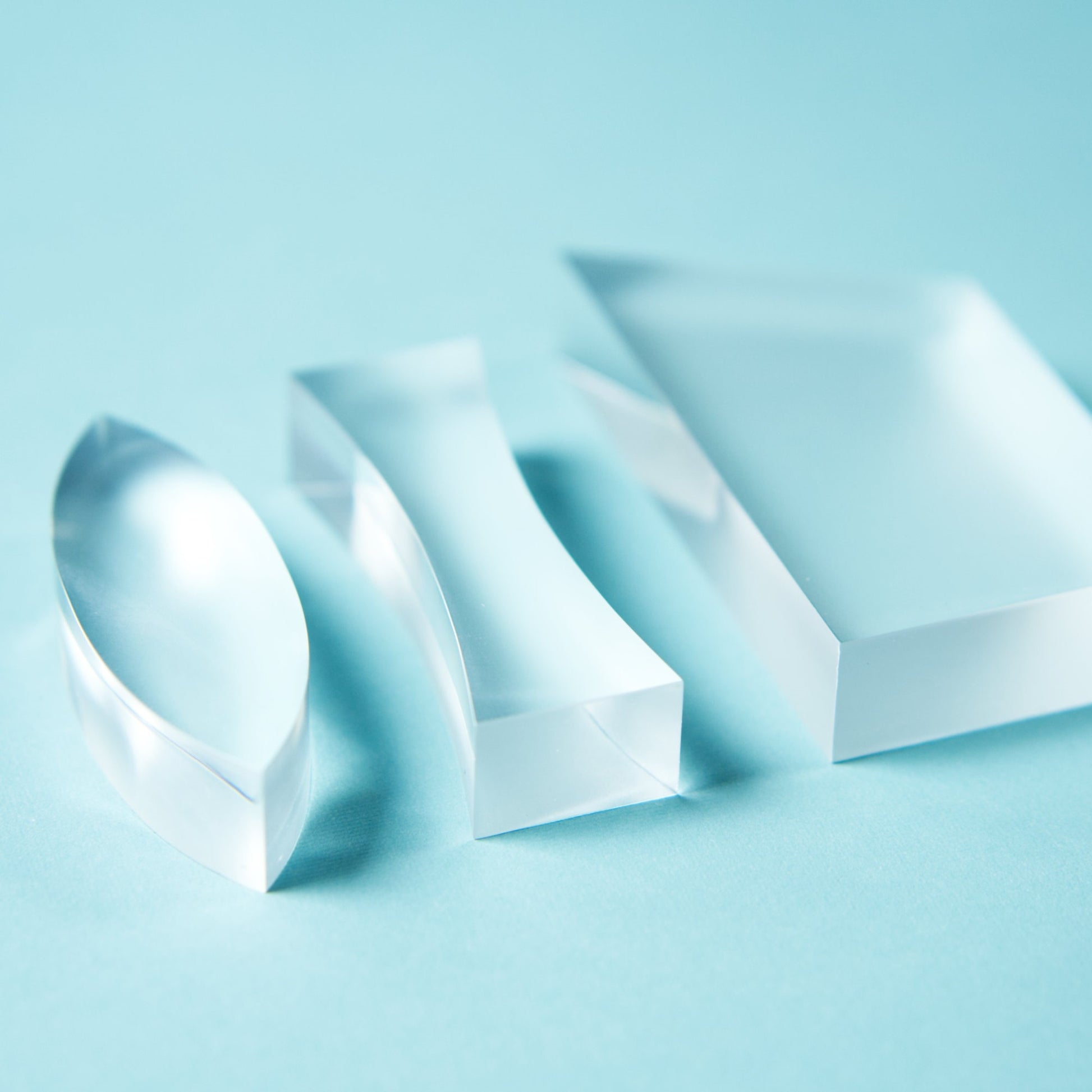 a set of three clear acrylic lenses for STEM optics experiments of refraction. One double concave lens, double convex lens, and trapezoidal prism lens