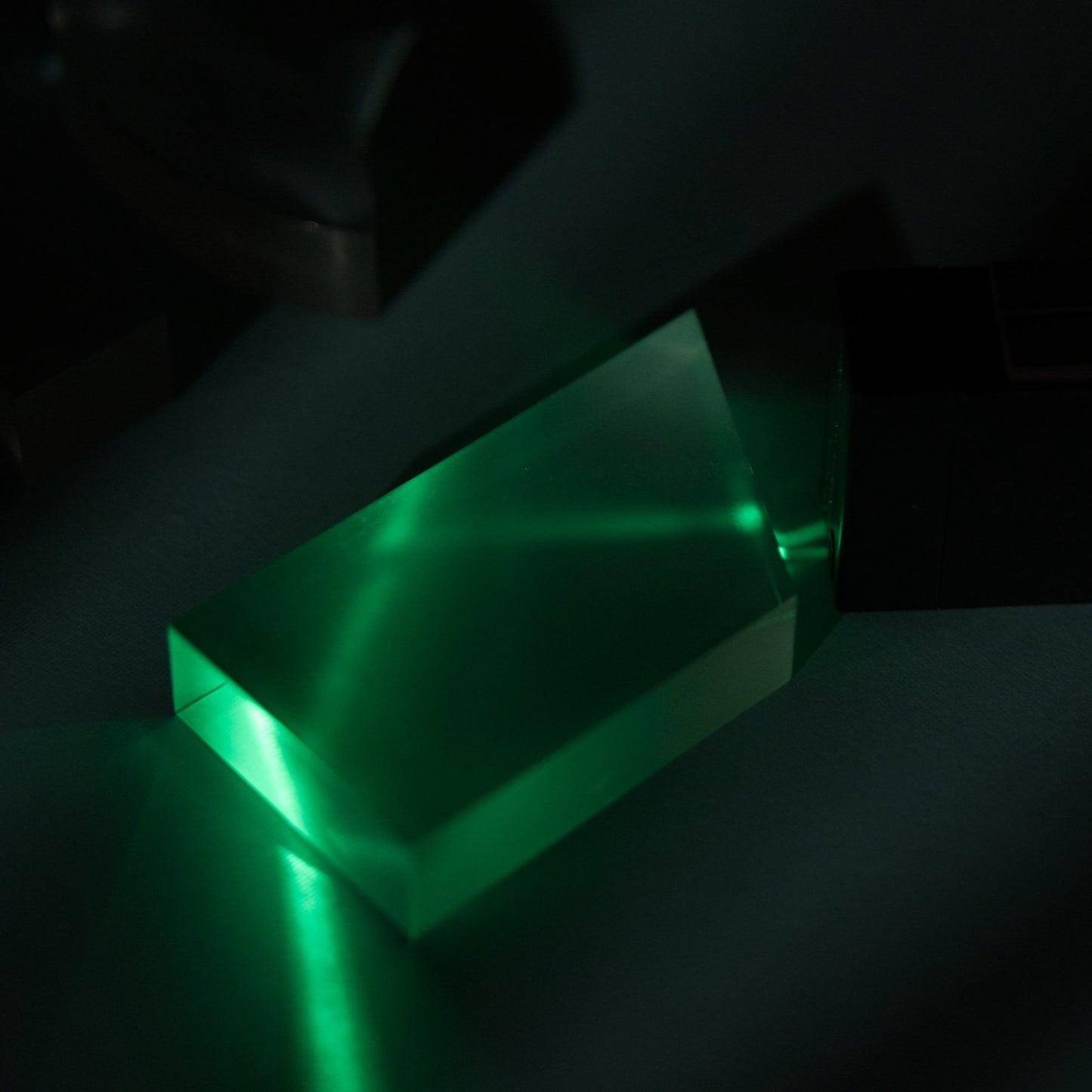 trapezoid prism with green ray box internal refraction experiment. Light is bouncing throught the 4 sided acrylic prism